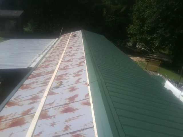 Old rusted panels beside newly installed green metal roofing — Wind Damage Roof Repair by Roofing Brothers in Shady Cove