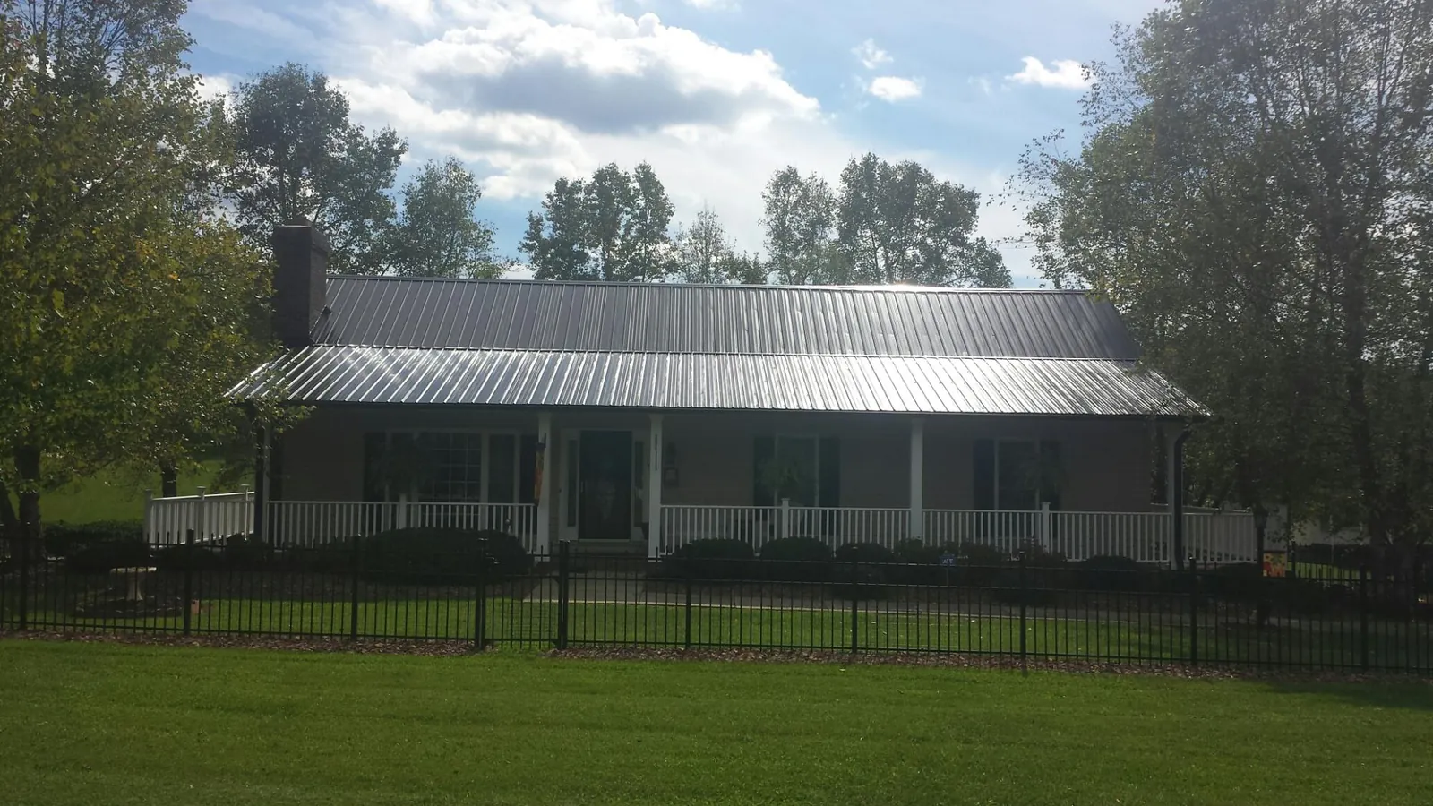 Gray metal roof on a brick ranch with a full width front porch — Gutter Guard Installation work by our crew in Shady Cove