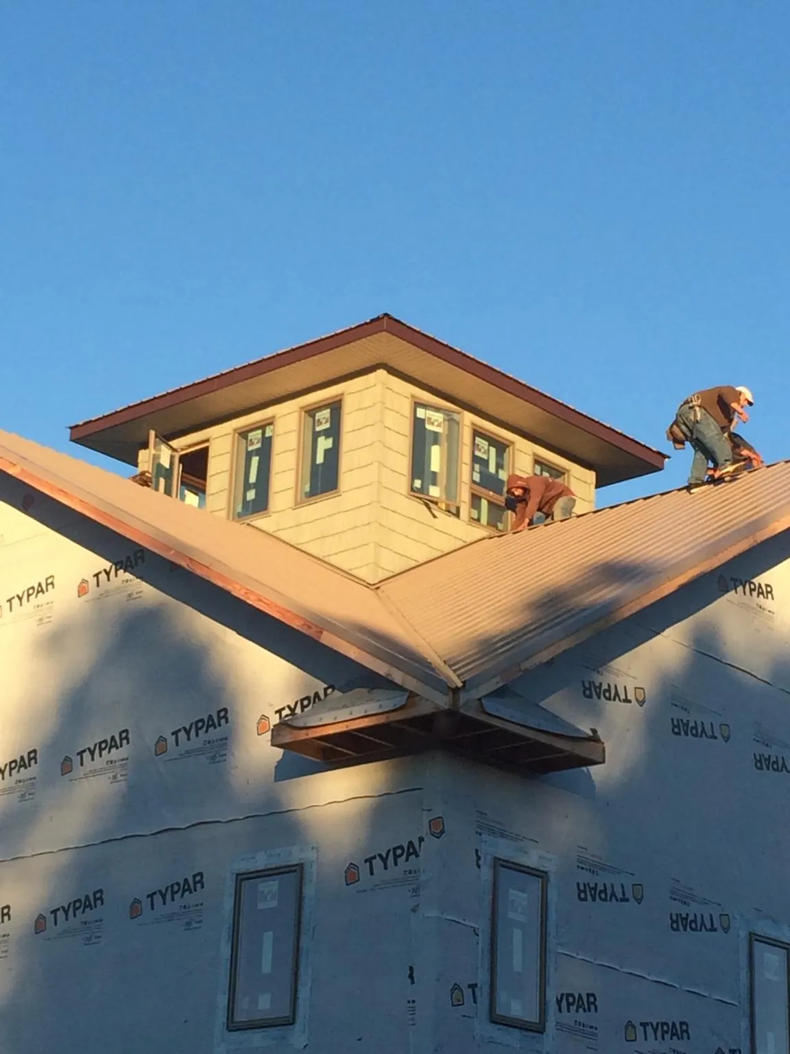 Roofers working around a rooftop cupola on a new metal roof at sunset — Roof Waterproofing in Shady Cove by Roofing Brothers